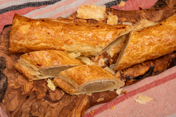 Fresh baked Dutch filled spicy cookies from puff pastry with almonds on wooden board close up