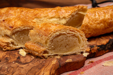 Fresh baked Dutch filled spicy cookies from puff pastry with almonds on wooden board close up