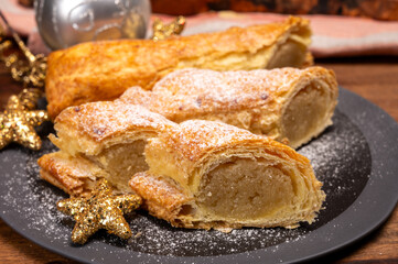 Christmas dessert, fresh baked Dutch filled spicy cookies from puff pastry with almonds on black board close up