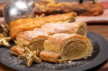 Christmas dessert, fresh baked Dutch filled spicy cookies from puff pastry with almonds on black board close up