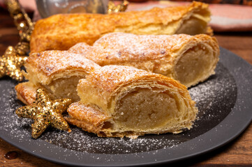 Christmas dessert, fresh baked Dutch filled spicy cookies from puff pastry with almonds on black board close up