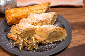 Christmas dessert, fresh baked Dutch filled spicy cookies from puff pastry with almonds on black board close up