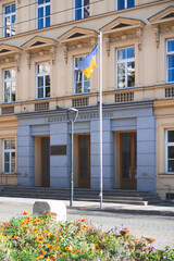 Fototapeta na wymiar Big Flag of Ukraine by Tall Pole and Yellow House