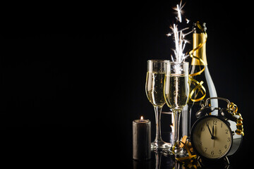 Champagne glasses and alarm clock on black background. New Year concept. New Year and Christmas...
