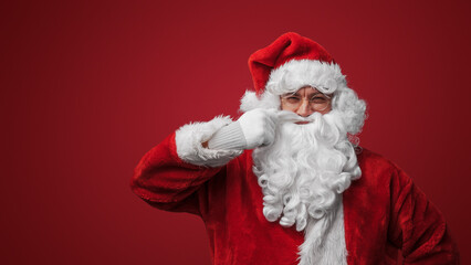 Portrait of christmas santa claus with glasses stroking his moustache looking at camera.