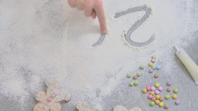 a child's hand draws 2024 in flour