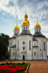 Fototapeta na wymiar The ancient Orthodox Church of St. Catherine in Chernihiv, with its white facade and iconic golden domes, harmonizing beautifully with the tranquil blue sky.
