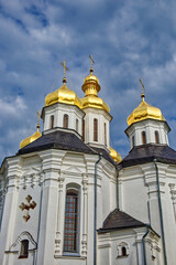 Fototapeta na wymiar A white church with golden domes, standing majestically against a backdrop of a blue sky with clouds. Catherine's Church is a church in Chernihiv, Ukraine. Golden domes against the sky.