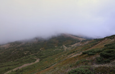 Morning view from the Dragobrat mountain peaks in Carpathian mountains, Ukraine. Cloudy and foggy landscape around Drahobrat Peaks in early morning