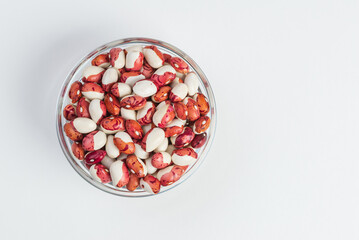 Glass bowl with red and white  kidney beans on white background isolated, top view whith copy space