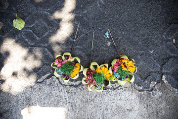 Three beautiful colorful opera bowls on the side of the road.  Flowers as an offering in Ubud, Bali