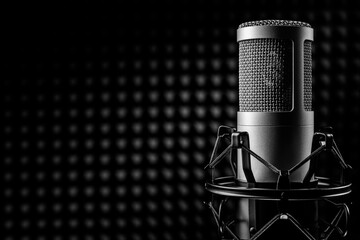 Professional studio microphone on the black sound proof panel. Recording studio, copy space.