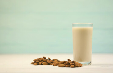 Glass of almond milk with almond nuts on white wooden table. Dairy alternative milk for detox, healthy eating and diets. Selective focus