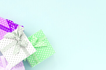 Pile of a small colored gift boxes with ribbons lies on a violet background. Minimalism flat lay top view.