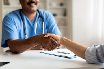Doctor Man Wearing Blue Uniform Shaking Hands With Female Patient In Clinic