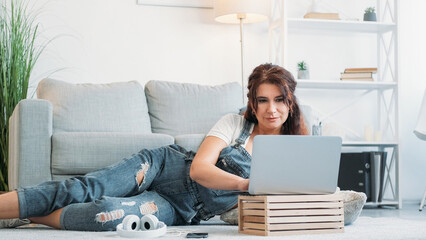 Virtual life. Happy woman. Computer technology. Middle-aged smiling lady laying sofa scrolling...