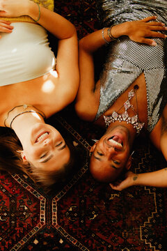 Analogue style portrait of two young multiracial adults in fashionable outfits on living room floor