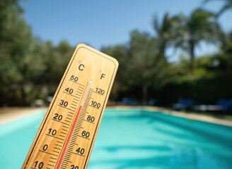 Wooden thermometer with red measuring liquid showing high temperatures on sunny day on background...