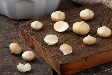 Raw macadamia nuts on cutting board. Selective focus.
