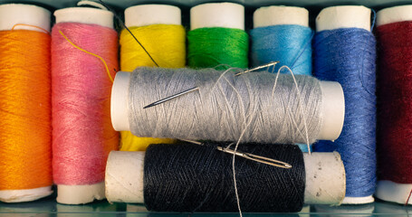 Box with multi-colored spools of thread. Sewing kit