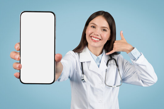 Female medic in white coat, call me gesture and blank phone screen