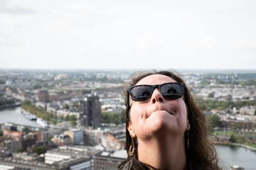 Wandaufkleber female tourist in Rotterdam look up at the Euromast tower which is seen in the reflection of her sunglasses. Dutch cosmopolitan city in background, clear day in the Netherlands for sightseeing © drew