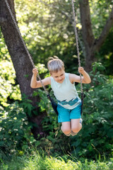 Happy child swings around on sunny nature background.