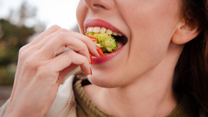 closeup woman eats broccoli on healthy lunch on street outdoors