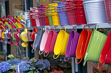 Colorful watering cans and buckets for plants at flower market in Paris.