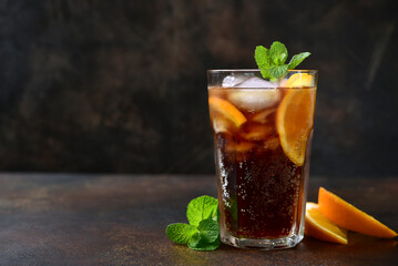 Cold summer soda cocktail with cola, dark rum and orange in a tall glass.