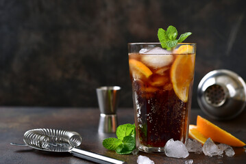 Cold summer soda cocktail with cola, dark rum and orange in a tall glass. - obrazy, fototapety, plakaty