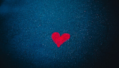 The symbol of the heart is painted in red paint on the wet asphalt. A declaration of love. Drawing.