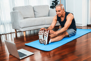 Active and fit senior man warmup and stretching before home exercising routine at living room while...