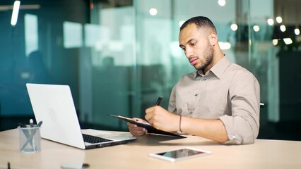 Focused businessman manager watching educational video on computer, writing notes in copybook improving professional knowledge distantly attending virtual event study MBA reskill upskill course remote