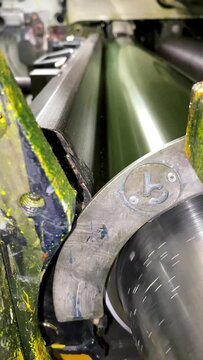Flexographic printing process on central drum machine. Video of an anilox roller attached to a print cylinder, the substrate is sandwiched between the plate and the print cylinder to transfer ink.