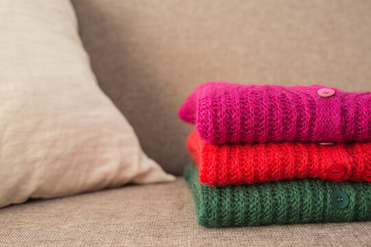 Stack of folded mohair cardigans in red, cherry and green colors. Cashmere Soft and fluffy wool. Stacked knitting patterns. Wool fabric