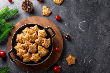 Fototapeta premium Festive Christmas cookies decorated with golden icing in a black plate. Dark grey background, top view, copy space for text
