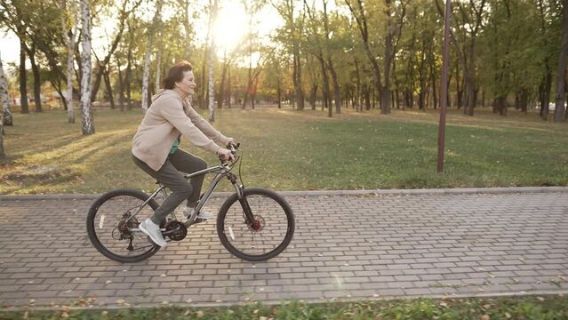 Mature woman riding bicycle at the sunset