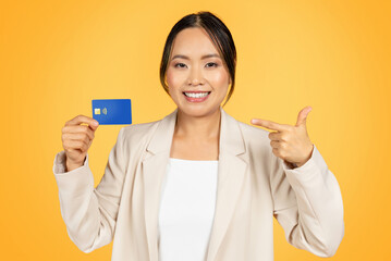 Positive young korean business lady in suit, point finger at credit card