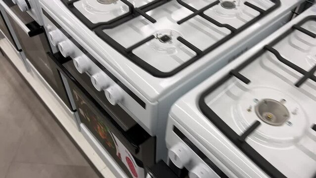New gas stoves are lined up in rows at the appliance store