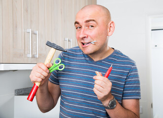 Imposing man holds in teeth of screws and holding hammer