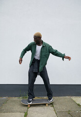 Gen Z black boy with blonde hair riding skateboard on sidewalk © Ejatu Shaw