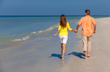 Rear View of Happy Couple Running Holding Hands on A Beach