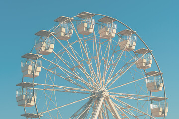 Giant white observation ferris wheel for panoramic view in amusement park is popular entertaining ride, shot against blue sky on bright sunny day