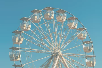 Deurstickers Giant white observation ferris wheel for panoramic view in amusement park is popular entertaining ride, shot against blue sky on bright sunny day © Bits and Splits