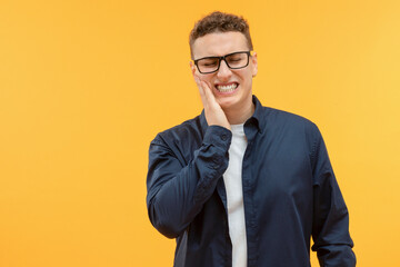 Unhappy young man touching his cheek, suffering from toothache