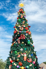 A large tree is displayed outside and covered in gold sparking garland, silver and gold balls,...
