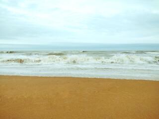 Fototapeta na wymiar Sea wave coming on a sandy beach. Cloudy sky. Serra, E. S. Espirito Santo, Brazil