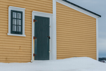 A bright and cheerful yellow country house with wood cape cod clapboard, white trim, and multiple...