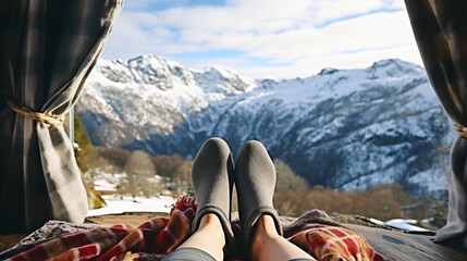 Feet in woolen socks by the holiday. A person sits under a blanket, relaxing by the warm fire and warming their feet in woolen socks. The concept of winter holidays and Christmas